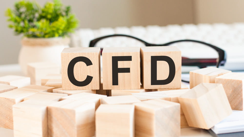 Cubes en bois épelant l'acronyme CFD posés sur un bureau de travail lumineux.