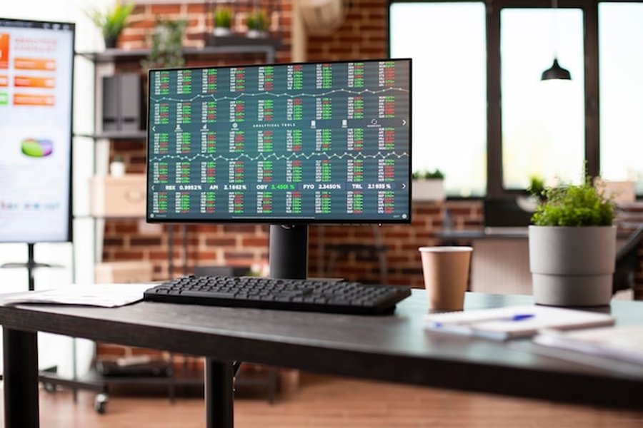 Un écran d'ordinateur affichant des données boursières complexes lors d'une formation trading en ligne dans un bureau moderne.