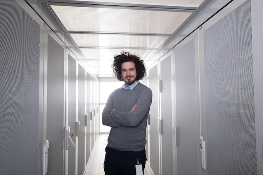 Un ingénieur informatique souriant au milieu de serveurs haute performance au sein de la crypto blockchain industry.