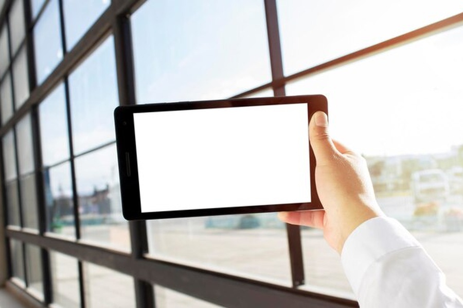 Une main tenant une tablette devant un immeuble de bureaux moderne pour comprendre scpi c'est quoi et comment investir.